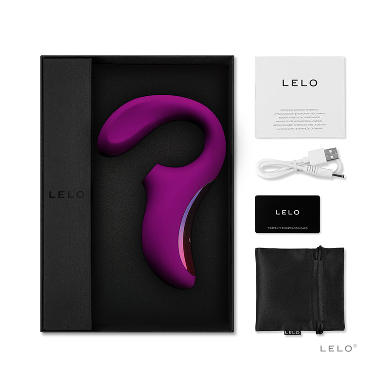 The image shows a deep rose colored vibrator with a sleek design, accompanied by a black USB charging cord, a satin storage pouch, and a warranty registration card. The vibrator is displayed in an open box with the brand LELO visible.