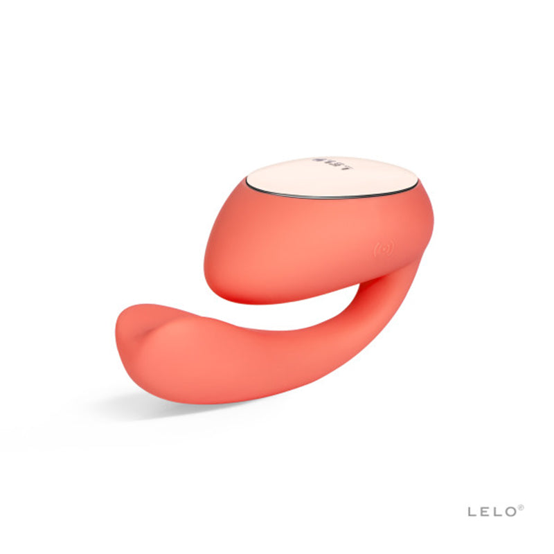 A coral red, sleek and modern rechargeable dual stimulator with a rotating insertable tail and a larger top, featuring a single button on the top section.